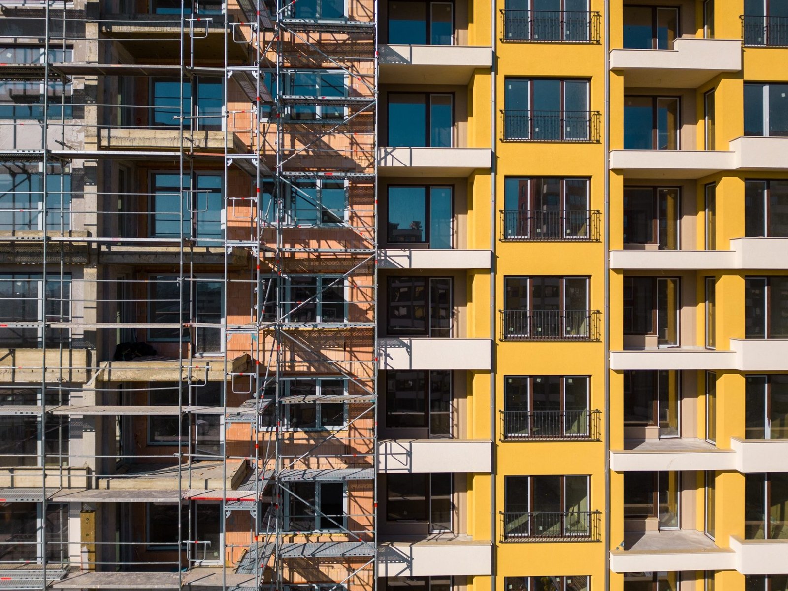 Drone flight along the facade of a modern apartment building under construction surrounded by