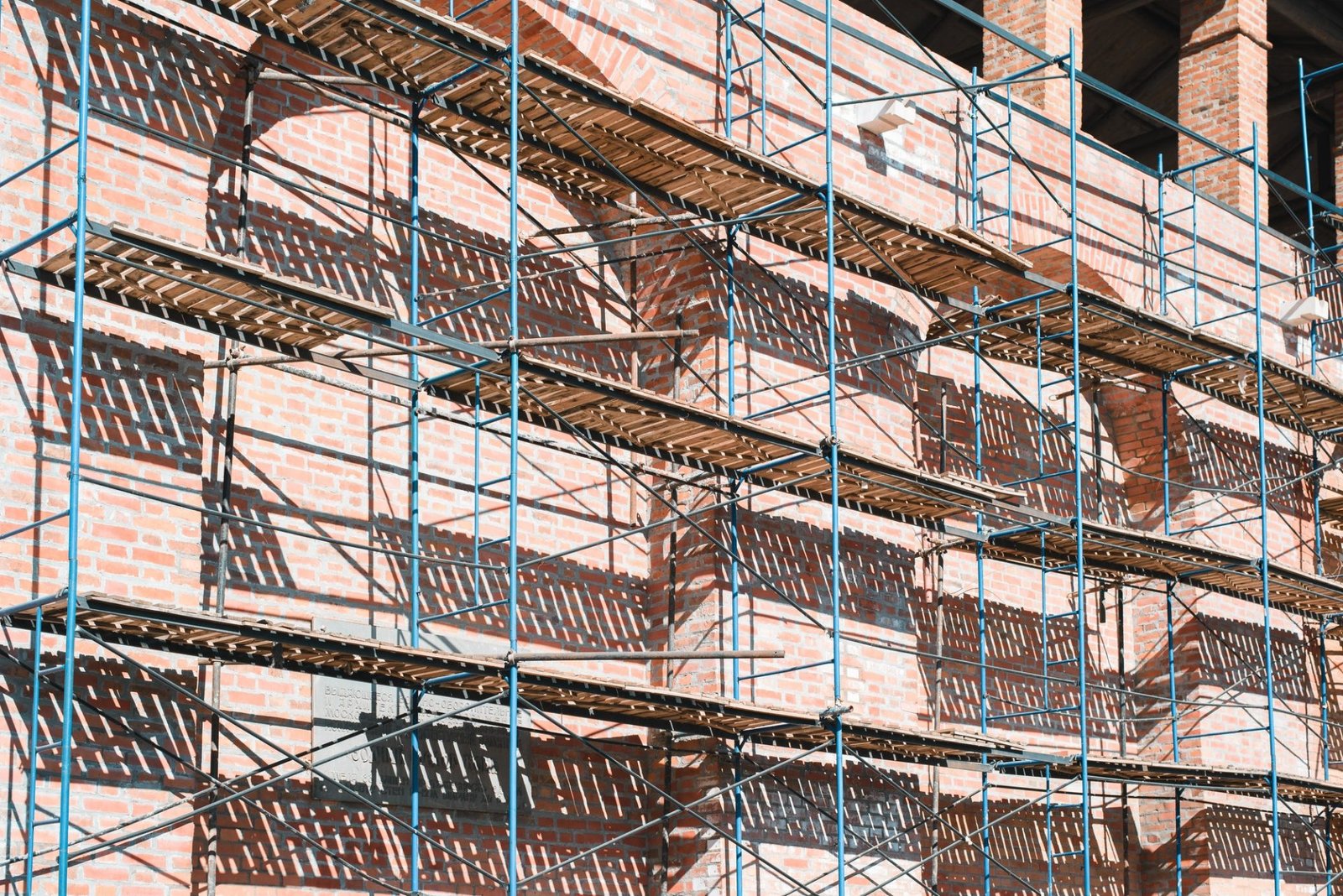 Reconstruction and restoration of red brick building, scaffolding at facade of old wall