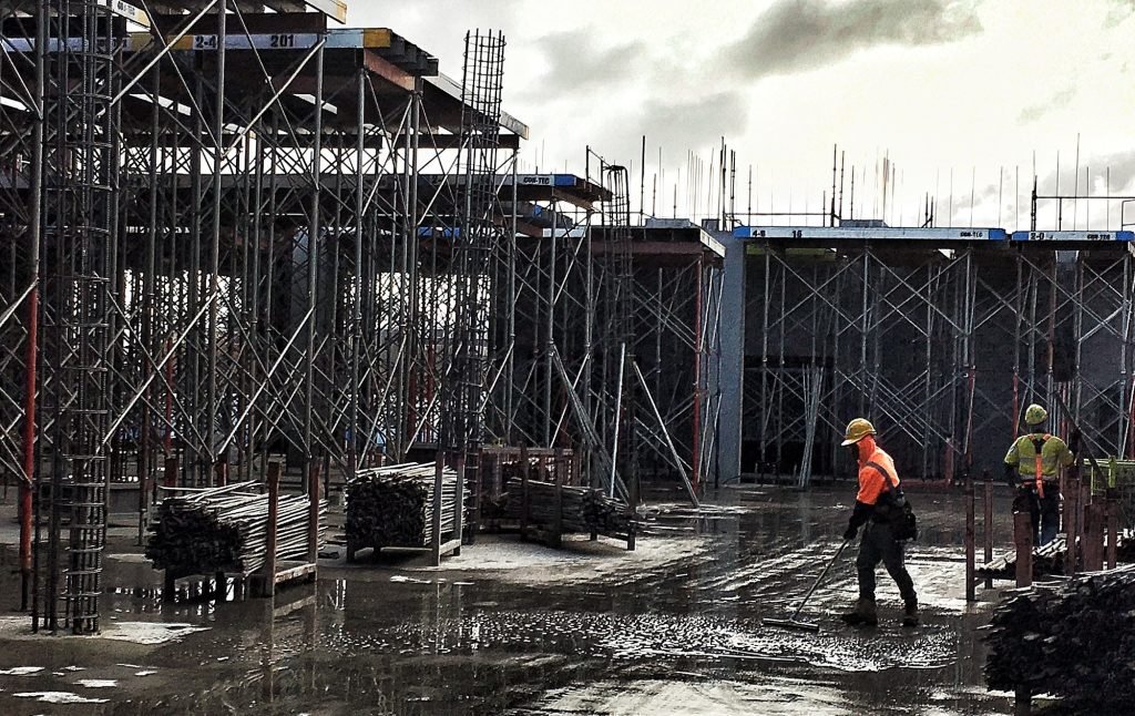 Two men working on a construction site surrounded by scaffolding
