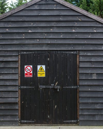 Flammable and no smoking sign on the doors on a large wooden shed.